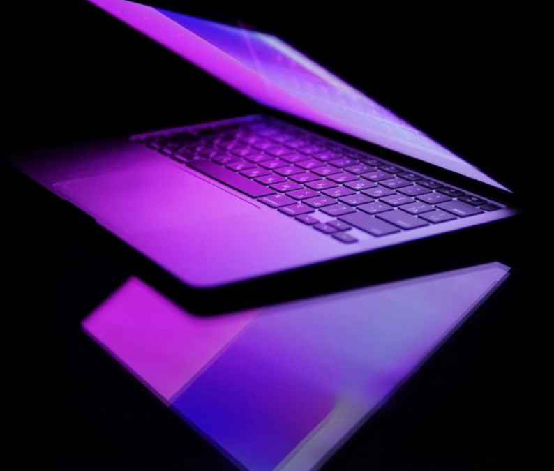 Ordinateur portable moderne avec éclairage violet représentant l’univers digital et la création web
