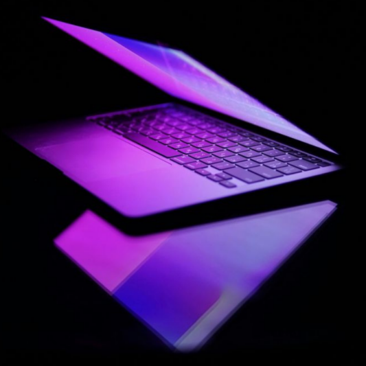 Ordinateur portable moderne avec éclairage violet représentant l’univers digital et la création web